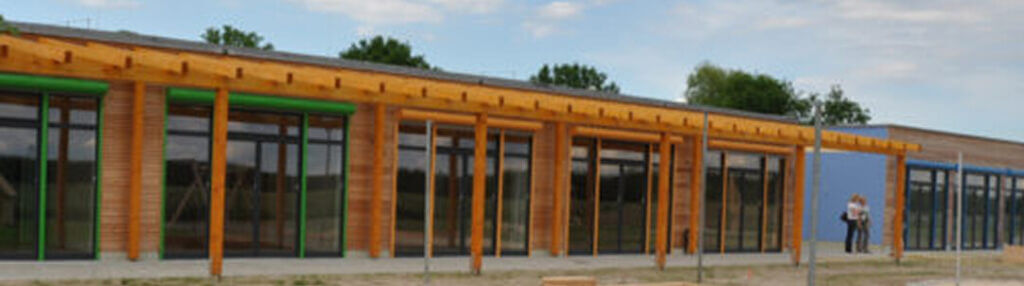 Flacher Holzbau mit Glasfassade und Vordach, nachhaltiges Bauen in Holzbauweise
