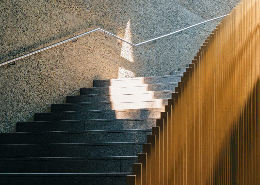 Granittreppe mit Edelstahlhandlauf und Holzverkleidung in einem Gebäude